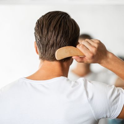 Young man looking in the mirror brushing hair